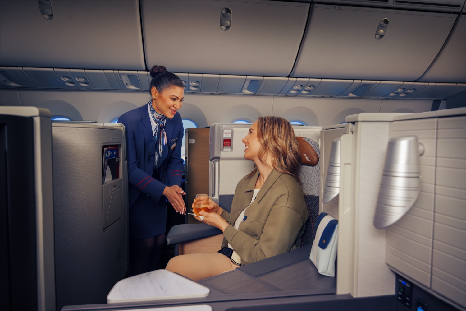 An American Airlines flight attendant serving a meal to a smiling customer